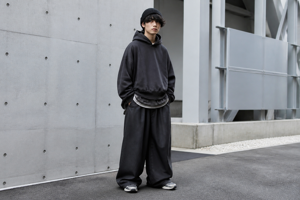 Person wearing an oversized hoodie, wide-leg pants, beanie, and sneakers in an urban street setting