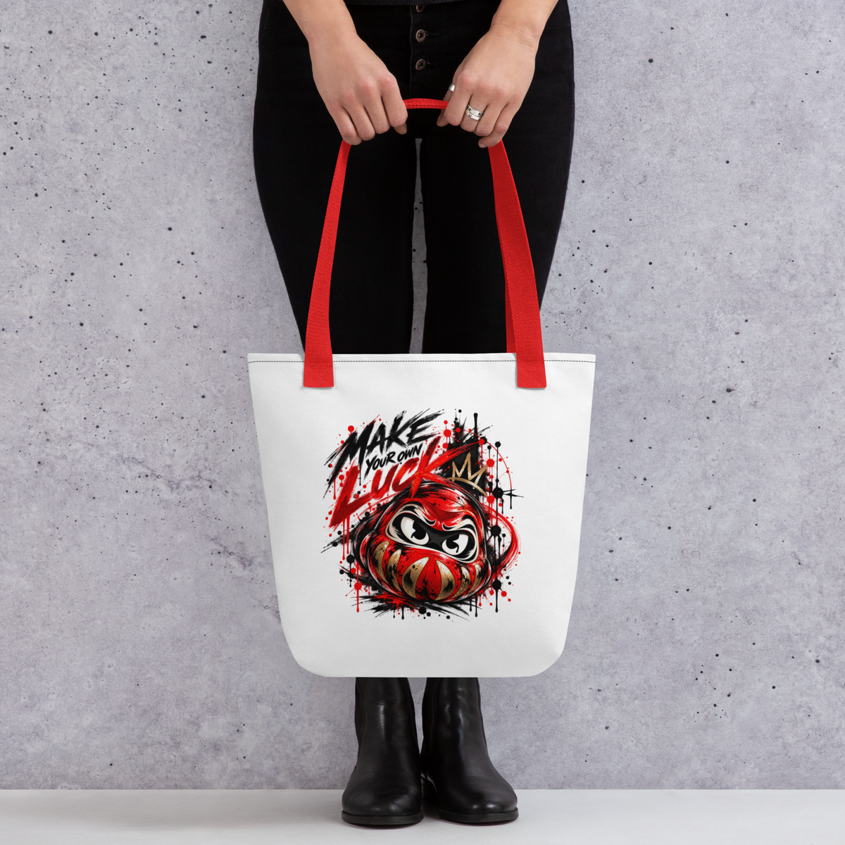 Spacious white tote bag featuring a bold red and black Daruma graphic with "Make Your Own Luck" text, held by a model.
