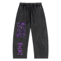 Black pants with a relaxed fit, featuring purple graphic stains and text. Designed for a streetwear style.