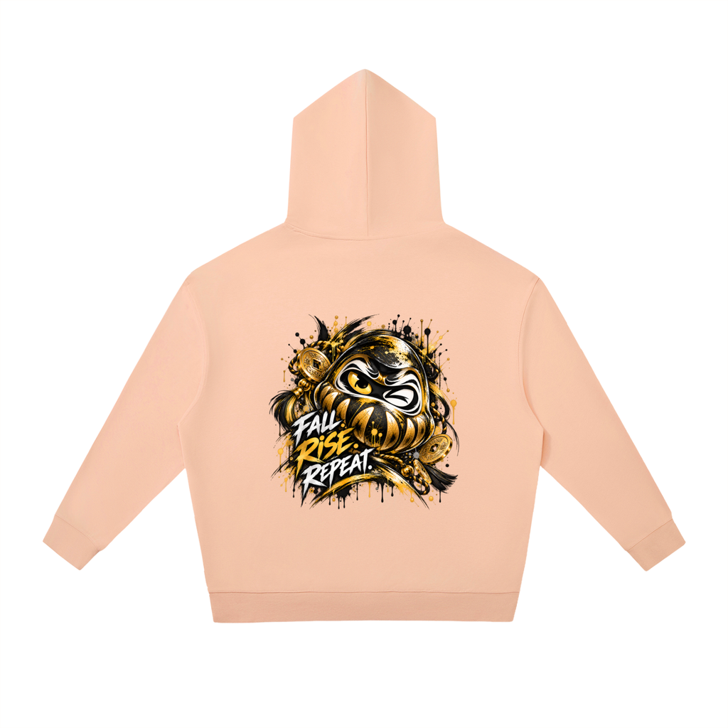 Oversized peach hoodie with a gold Daruma graphic and "FALL RISE REPEAT" text, featuring a relaxed fit and kangaroo pocket.