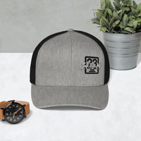 Casquette trucker Signature gris chiné et noir Ink Pick Me posée sur une table – vue de face