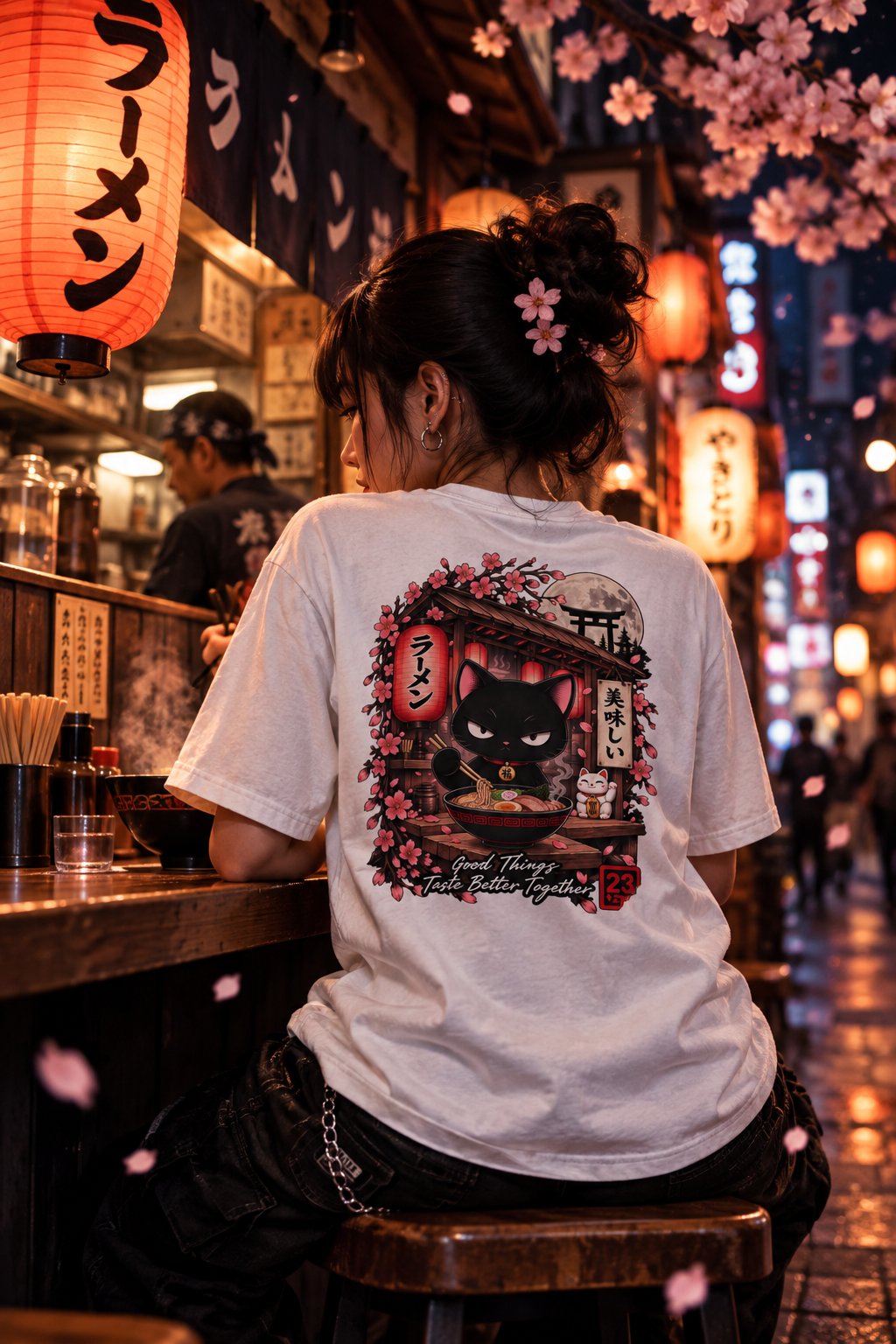 T-shirt streetwear japonais Lucky Ramen porté dans un bar à ramen de nuit, sakura et lanières rouges